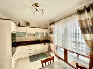 a kitchen with white cabinets and a large window at Agroturystyka Pod Jodłami in Kołaki Wietrzychowo