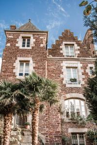 a brick building with a palm tree in front of it at Castel Jolly in Rennes