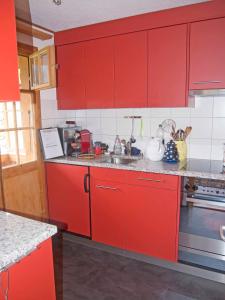 a kitchen with red cabinets and a sink at Ferienwohnung Chalet Zwirbeli in Adelboden