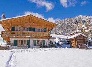 a log cabin in the snow with a car parked in front at Ferienwohnung Chalet Zwirbeli in Adelboden