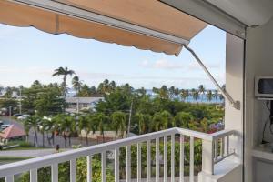 a balcony with a view of the beach and palm trees at Agréable studio face à la plage :) in Le Moule