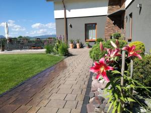 einen Backsteinsteg vor einem Haus mit Blumen in der Unterkunft Pension Lunatyk in Liptovský Mikuláš