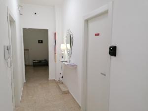 a hallway with white walls and a mirror on the wall at Tanzi Home in Bari