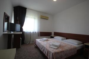 a hotel room with a bed and a television at KorMal Guest House in Vityazevo