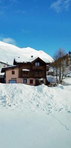 a house covered in snow with a pile of snow at Al Dos in Livigno