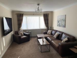 a living room with a leather couch and a tv at Holm from Home in Inverness