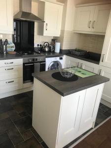 a kitchen with white cabinets and a black counter top at Newcastle Seafront Apartment with Wifi and Parking in Newcastle