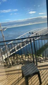 uma vista para o oceano a partir de uma varanda com um banco em Newcastle Seafront Apartment with Wifi and Parking em Newcastle