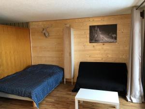 a bedroom with a bed and a wooden wall at Le Relai S34 - Grand et lumineux studio avec coin montagne 4-6 pers avec WIFI, 50m des pistes, grand balcon exposé SUD, DRAPS NON COMPRIS in Saint-Jean-dʼAulps