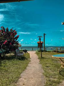 a path leading to a beach with a bench and a tree at Chez Max Pousada in Morro de São Paulo