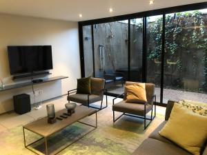 a living room with a couch and chairs and a tv at Ten On Lane in Polokwane