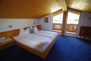a bedroom with a large bed and a balcony at Hotel-Pension Heike in Kitzbühel