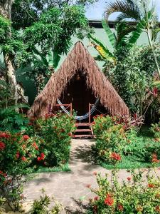 a small hut with a straw roof in a garden at Chez Max Pousada in Morro de São Paulo