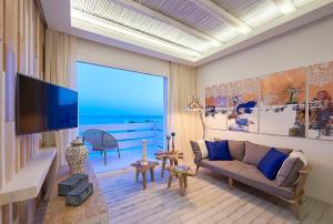 a living room with a couch and a flat screen tv at Artemis Seaside Resort in Paliochori