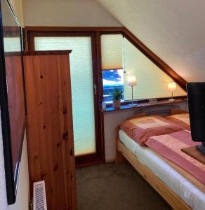 a bedroom with a bed and a window with a tv at Gemütliches Zimmer zentral in der Lüneburger Heide in Schneverdingen