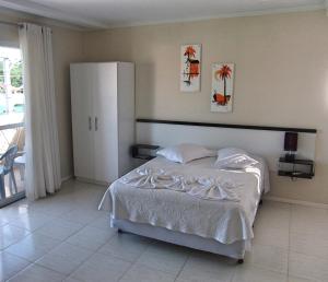 a bedroom with a white bed and a large window at Pousada Mar Azul in Bombinhas