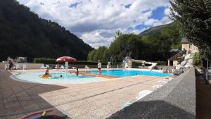 a swimming pool in a resort with people in it at Appartement GAVARNIE Résidence Les 3 Cirques in Gèdre