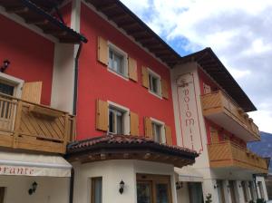 czerwono-biały budynek z drewnianymi balkonami w obiekcie Hotel Dolomiti Saone w mieście Tione di Trento
