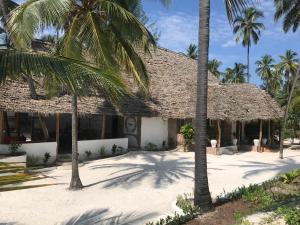 a building with palm trees in front of it at Bahati Hotel Villas in Bwejuu