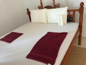 a white bed with white pillows and a red blanket at Bahati Hotel Villas in Bwejuu