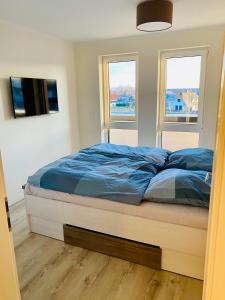 a bed in a bedroom with two windows at Haus Meerruhe Karlshagen Apartment 7 in Ostseebad Karlshagen