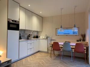 uma cozinha com armários brancos e uma mesa e cadeiras em WAD NOU Terschelling heerlijk duurzaam chalet! em Midsland