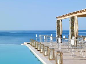 a boardwalk with chairs and tables next to the ocean at Artemis Seaside Resort in Paliochori