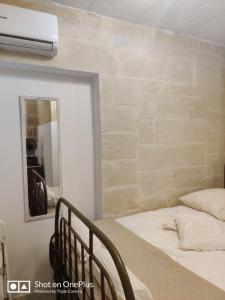 a bedroom with a bed and a mirror at Semi-basement, cosy apartment interconnected to our residence a traditional Maltese townhouse in Senglea