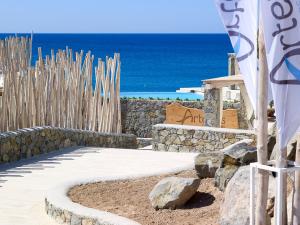 a pathway with a stone wall and the ocean at Artemis Seaside Resort in Paliochori