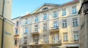 a large white building with windows on a street at Apartamenty Bracka 6 in Krakow