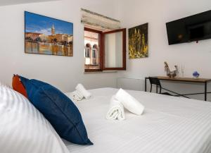 a bedroom with a white bed with blue pillows at B&B Rooms Old Town Rab in Rab