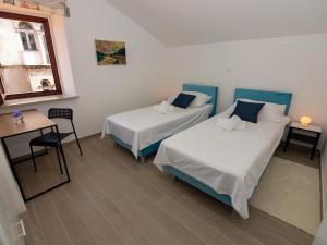 a room with two beds and a table and a window at B&B Rooms Old Town Rab in Rab