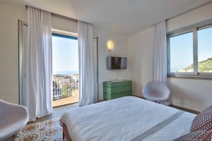 a bedroom with a bed and two chairs and a window at Home del Corso in Capo dʼOrlando