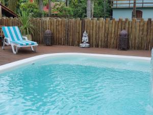 una piscina con una silla y una silla en La Ferrugem Suites - 100 mts da Praia, en Garopaba