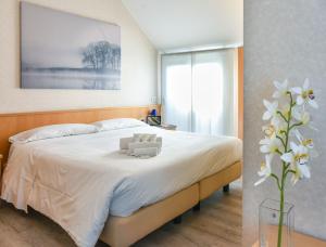 1 dormitorio con 1 cama con sábanas blancas y un jarrón de flores en Residence Cimarosa, en Milán