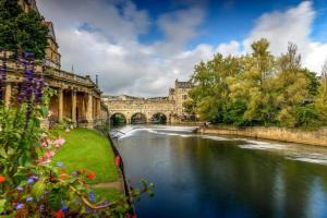 a river in front of a building with a bridge at Beautiful Bath Apartment in iconic Milsom Street Location in Bath