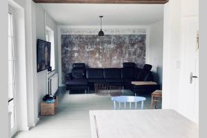 a living room with a black couch and a table at Ferienhaus Talblick in Alpenrod