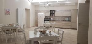 a kitchen with white tables and chairs and a white refrigerator at B&B I Pini in Recale