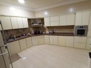 a large kitchen with white cabinets and appliances at شقة دورين 4 غرف نوم في منطقة هادئه - لغير المدخنين - تقع في الدور الأول - لايوجد مصعد - تبعد عن وسط بريده 8 دقائق in Buraydah