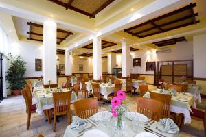 a dining room with tables and chairs with white tablecloths at Club Aphrodite in Erimi