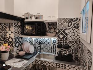 - une cuisine avec des murs carrelés noirs et blancs et un évier dans l'établissement Luxury House Love, à Milan