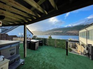 a patio with a view of a body of water at Amazing Alps and Loch views - HOT TUB and pet friendly in Arrochar