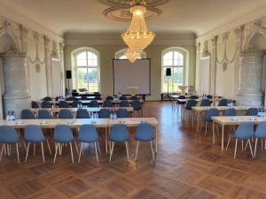 uma grande sala com mesas e cadeiras e uma tela de projeção em Schloß Vietgest em Vietgest