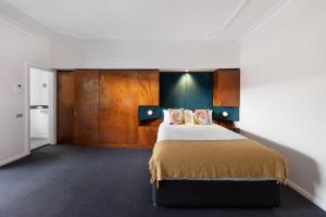 a bedroom with a large bed and wooden cabinets at Regents Court Sydney in Sydney