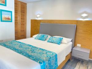 a bedroom with a white bed with blue pillows at Hotel Agua Dulce in Boca Chica