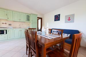 a kitchen with green cabinets and a wooden table and chairs at Residence SardegnaSummer Li Mori in Budoni