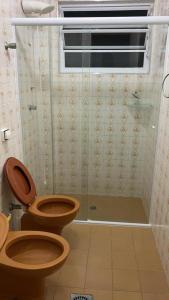 a bathroom with a toilet and a glass shower at Enseada à 450m da praia in Guarujá +3 photos