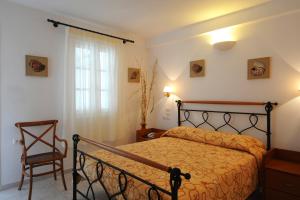 a bedroom with a bed and a chair and a window at Vardia Bay Studios in Karavostasi