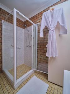 baño con ducha y albornoz colgado en la pared en City View Motel, en Warwick