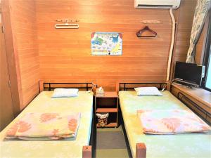 a bed room with two beds and a desk at Shiraho Friends House in Ishigaki Island